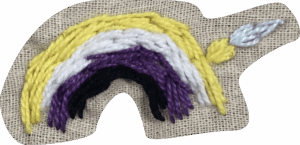 Jednoduchá výšivka duhy v nebinárních barvách, což je žlutá, bílá, fialová a černá. Nad duhou je vyšitý malý štětec, co ji jako maluje. Výšivka se na webu opakuje a slouží jako přidělovací ikonka.