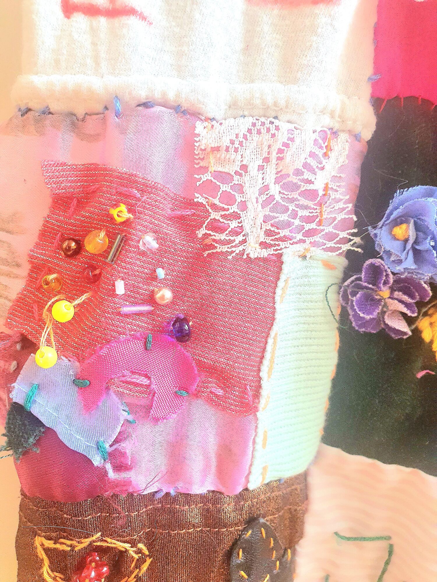 Čtyři detailní fotky zachycující barevné látkové čtverečky. Jsou na nich přišité pestrobarevné tvary, výšivky bavlnkami, různé korálky, krajky i nápisy fixou jako Prajd pičo. 